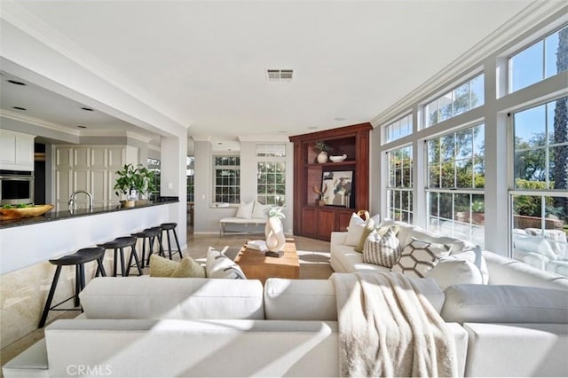 living room featuring ornamental molding, sink, and plenty of natural light