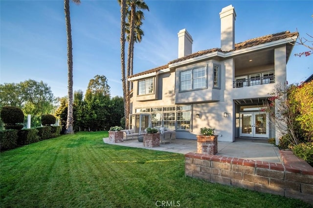 rear view of house with a lawn, a patio, and french doors