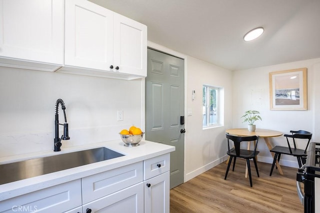 kitchen with white cabinetry, sink, and light wood-type flooring