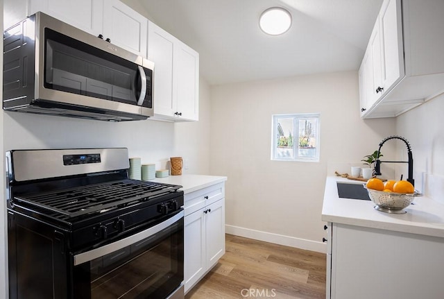 kitchen featuring white cabinetry, appliances with stainless steel finishes, light hardwood / wood-style floors, and sink