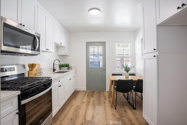 kitchen featuring sink, light hardwood / wood-style flooring, stainless steel appliances, and white cabinets