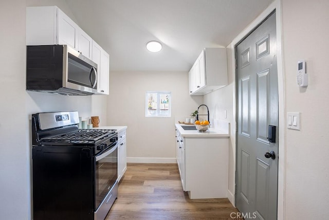 kitchen featuring white cabinetry, appliances with stainless steel finishes, sink, and light hardwood / wood-style floors