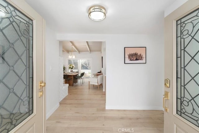 foyer featuring beamed ceiling, wood ceiling, light hardwood / wood-style flooring, and a notable chandelier