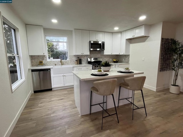 kitchen featuring a kitchen island, white cabinetry, sink, a kitchen breakfast bar, and stainless steel appliances