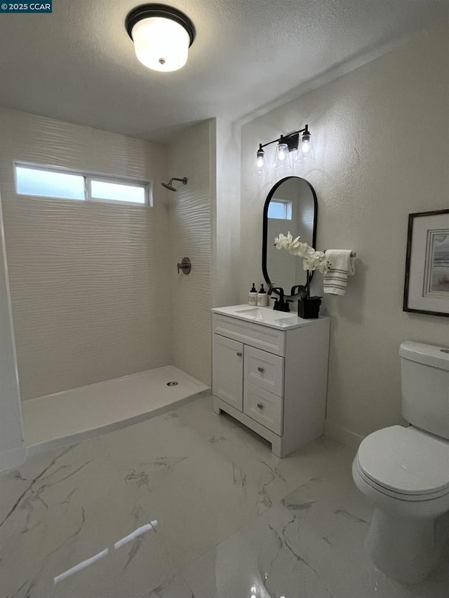 bathroom featuring vanity, toilet, a textured ceiling, and a tile shower