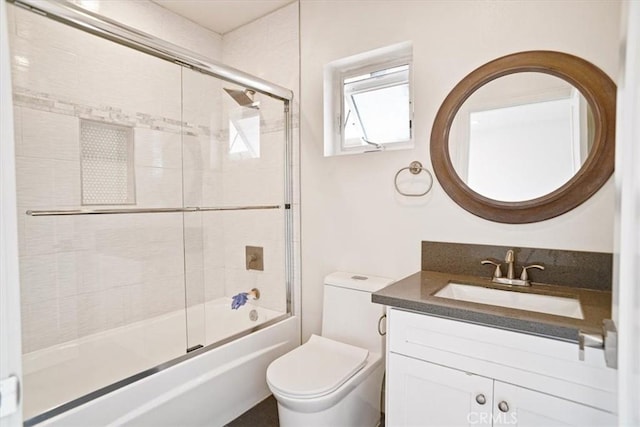 full bathroom featuring toilet, vanity, and bath / shower combo with glass door