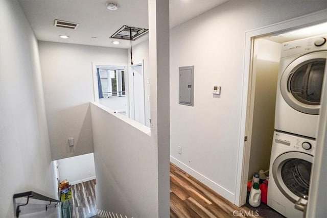 clothes washing area with dark hardwood / wood-style floors, electric panel, and stacked washer and clothes dryer