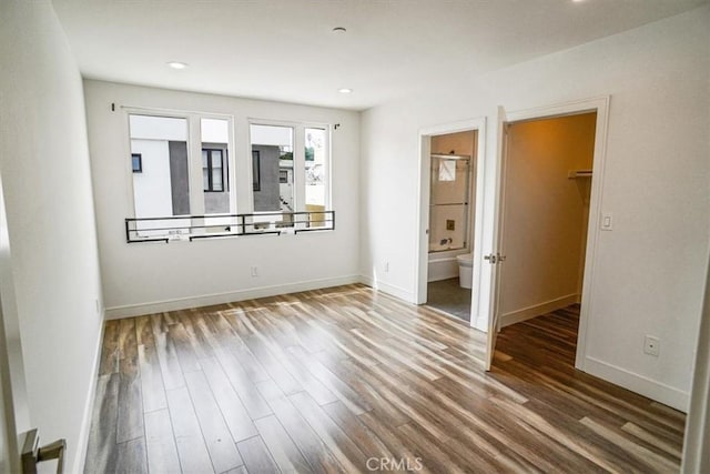 unfurnished bedroom featuring hardwood / wood-style floors and ensuite bath