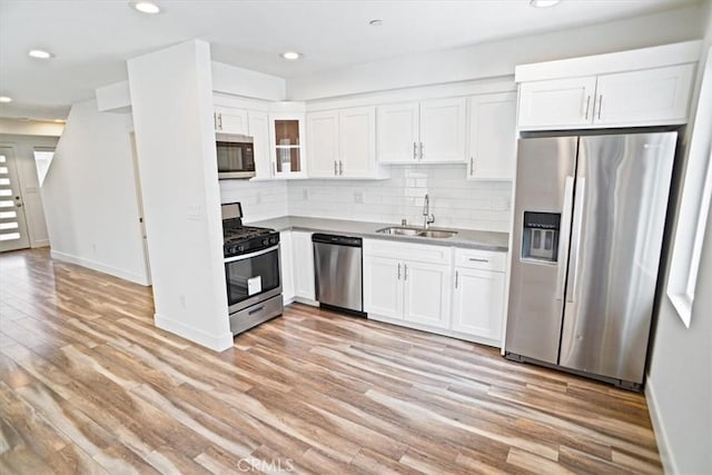 kitchen with stainless steel appliances, white cabinetry, sink, and decorative backsplash