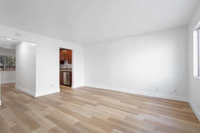 unfurnished living room with sink and light hardwood / wood-style floors