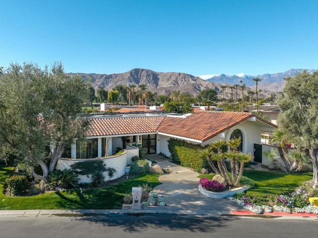 view of front of house with a mountain view and a front lawn