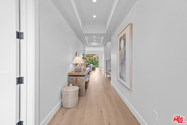 hall featuring a tray ceiling and light wood-type flooring