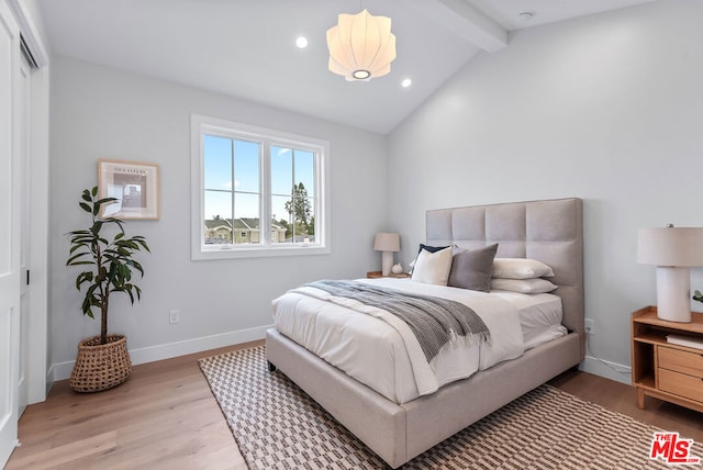 bedroom with lofted ceiling with beams, a closet, and light wood-type flooring