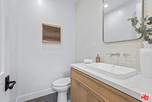 bathroom featuring tile patterned flooring, vanity, tasteful backsplash, and toilet