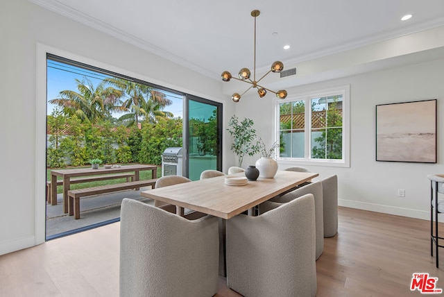 dining area featuring ornamental molding, an inviting chandelier, and light hardwood / wood-style floors