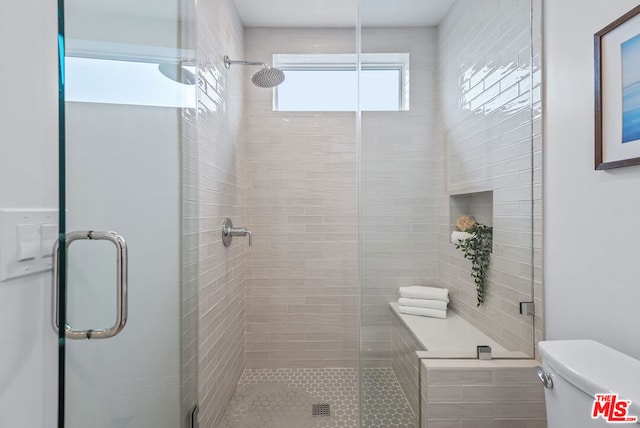 bathroom featuring toilet and a shower with shower door