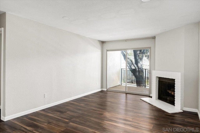 unfurnished living room featuring dark hardwood / wood-style flooring and a brick fireplace