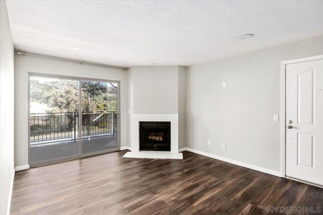 unfurnished living room with wood-type flooring, a brick fireplace, and a textured ceiling