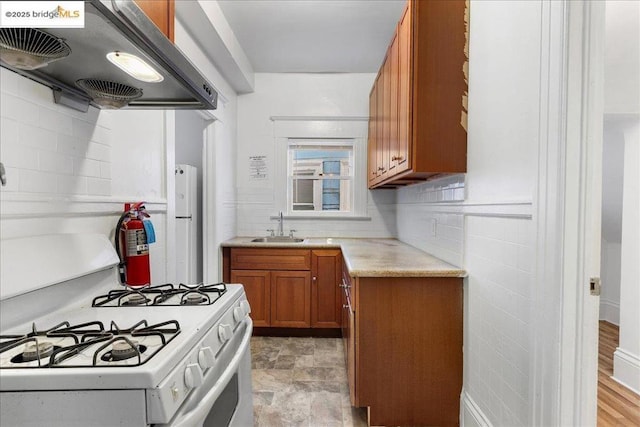 kitchen featuring white appliances, ventilation hood, sink, and backsplash