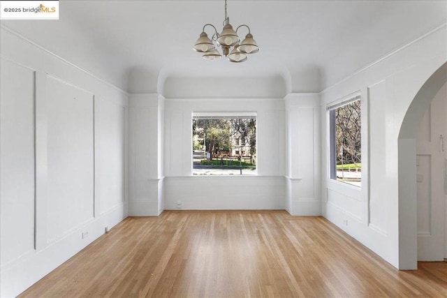 unfurnished room with an inviting chandelier and light hardwood / wood-style floors