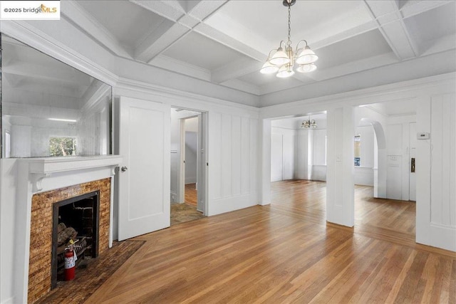 living room with coffered ceiling, hardwood / wood-style floors, beamed ceiling, and a chandelier