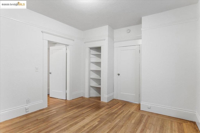 unfurnished bedroom with hardwood / wood-style floors, a textured ceiling, and a closet