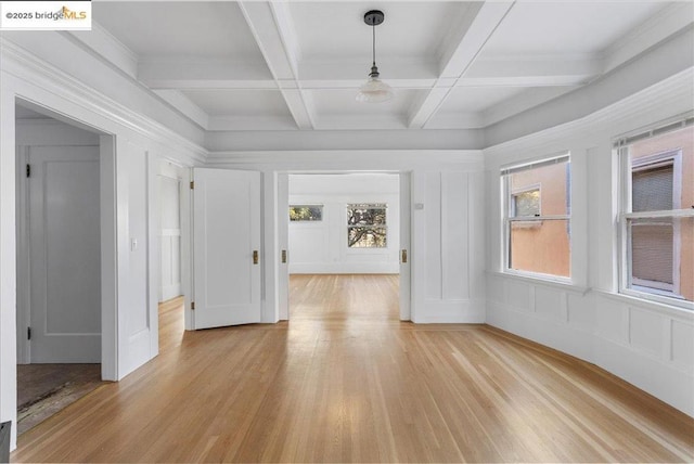 unfurnished room with coffered ceiling, beam ceiling, and light hardwood / wood-style flooring