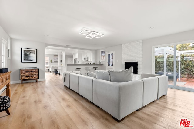 living room with light hardwood / wood-style floors and a brick fireplace