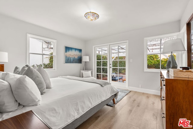 bedroom featuring multiple windows, access to outside, light hardwood / wood-style floors, and french doors