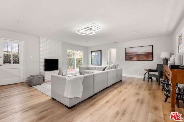 living room featuring a brick fireplace and light hardwood / wood-style flooring