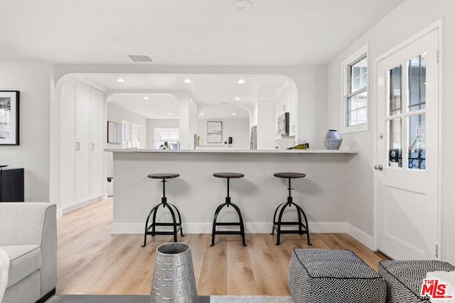 kitchen featuring white cabinetry, a kitchen bar, kitchen peninsula, and appliances with stainless steel finishes