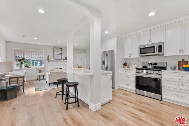 kitchen with stainless steel appliances, white cabinetry, a center island, and a breakfast bar area