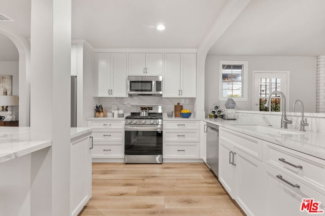 kitchen featuring white cabinetry, appliances with stainless steel finishes, light stone countertops, and sink