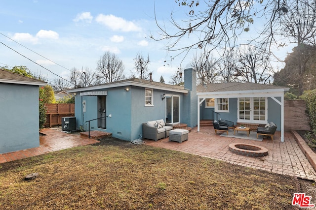 back of house with a lawn, an outdoor living space with a fire pit, a patio, and central air condition unit