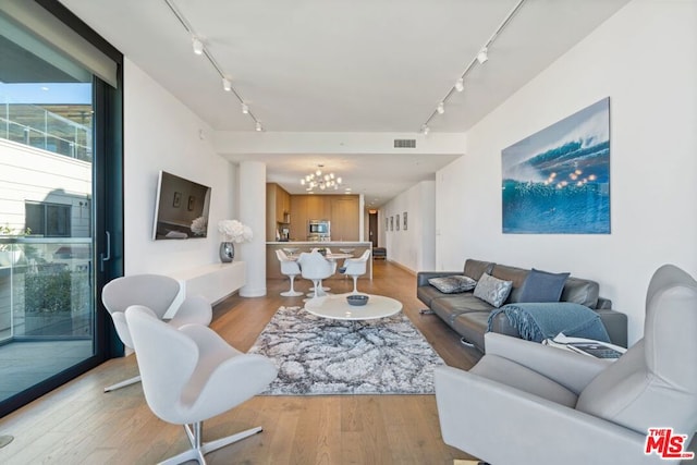 living room featuring an inviting chandelier, light hardwood / wood-style floors, and rail lighting