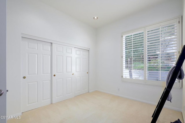 unfurnished bedroom featuring light carpet and a closet