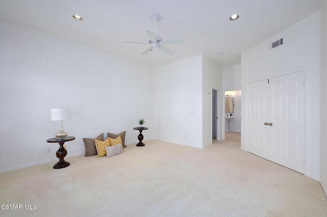 living area with light carpet and ceiling fan