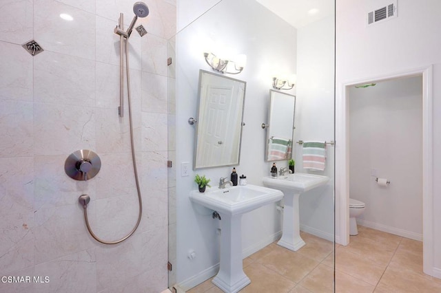 bathroom with toilet, tile patterned flooring, and dual sinks