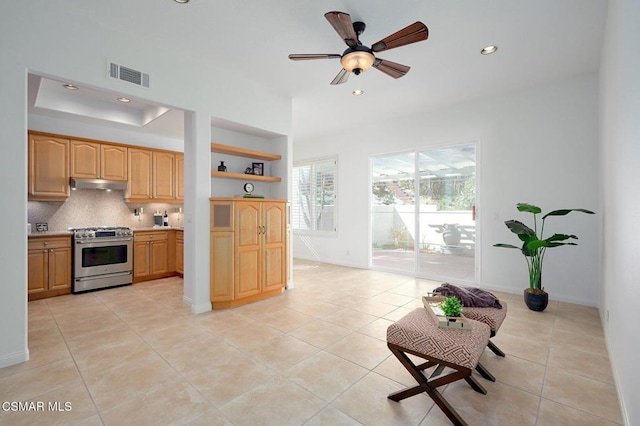 kitchen featuring tasteful backsplash, light tile patterned floors, gas range, and ceiling fan