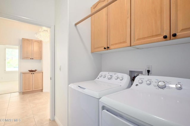 clothes washing area with cabinets, light tile patterned flooring, and washer and dryer