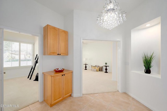 hall featuring an inviting chandelier and light colored carpet