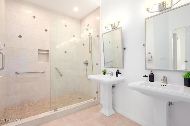 bathroom with double sink, tile patterned flooring, and a tile shower