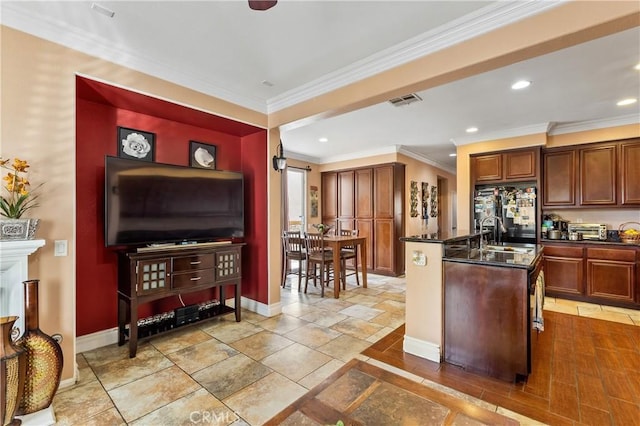 kitchen featuring crown molding, black fridge, sink, and a kitchen island with sink