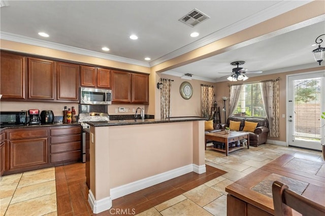 kitchen featuring ornamental molding, stainless steel appliances, an island with sink, and dark stone countertops