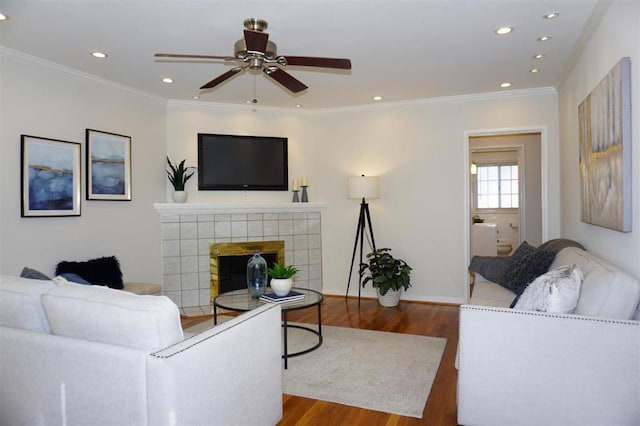 living room featuring dark hardwood / wood-style flooring, crown molding, a tile fireplace, and ceiling fan