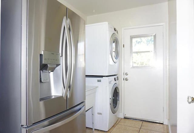 laundry area featuring stacked washer and dryer and light tile patterned flooring