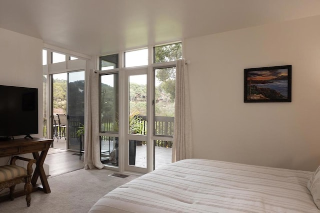 bedroom with access to exterior, light colored carpet, and expansive windows