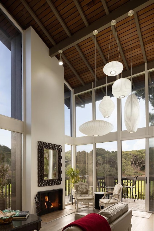 unfurnished sunroom with an outdoor fireplace, a healthy amount of sunlight, and beam ceiling