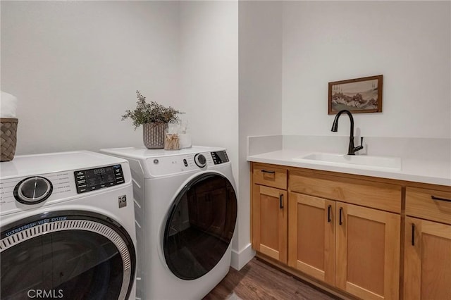 laundry room with cabinets, washing machine and dryer, sink, and dark hardwood / wood-style floors