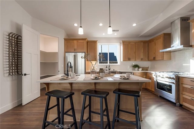 kitchen featuring high end appliances, wall chimney exhaust hood, and a kitchen island with sink